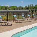 Inviting outdoor pool area with comfortable lounge chairs under a bright blue sky, ideal for relaxation and leisure.