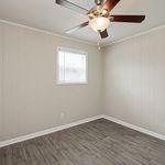 Bright room with sleek laminate flooring, neutral walls, and a modern ceiling fan, perfect for versatile styling.