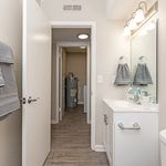 Bright and modern bathroom with sleek vanity, elegant lighting, and convenient laundry access.