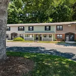 Charming townhouse with a classic facade nestled in a lush green setting, offering a peaceful and friendly neighborhood vibe.