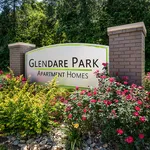 Welcoming entrance sign of Glendare Park Apartment Homes, surrounded by vibrant flowers and lush greenery.