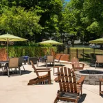 Inviting outdoor patio with wooden chairs and tables under vibrant green umbrellas, perfect for relaxation and social gatherings in a lush garden setting.