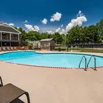 Inviting outdoor pool area with crystal-clear water, surrounded by lush greenery and lounge chairs under a bright blue sky.