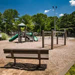 Inviting playground area with slides and swings surrounded by lush greenery, perfect for family fun on a sunny day.