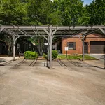 Charming outdoor view featuring a stylish pergola, lush greenery, and a rustic brick garage in a serene setting.