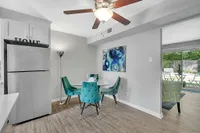 Chic dining area with vibrant teal chairs, modern art, and natural light from sliding doors leading to a charming patio.