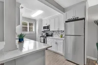 Modern kitchen with sleek stainless steel appliances, elegant white cabinetry, and stylish tile backsplash, offering a bright and inviting atmosphere.