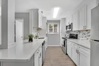 Chic modern kitchen with sleek white cabinets, stainless steel appliances, and stylish tile backsplash, perfect for culinary enthusiasts.