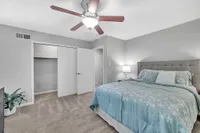 Inviting bedroom featuring a plush bed with floral bedding, elegant lighting, and ample closet space, perfect for relaxation and comfort.