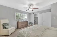 Inviting bedroom with plush bedding, modern dresser, and serene natural light enhancing the tranquil atmosphere.