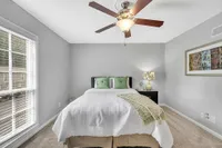 Inviting bedroom with plush bed, stylish decor, and natural light from large window, perfect for relaxation.