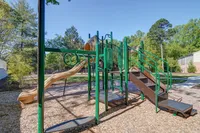 Inviting outdoor playground featuring slides and climbing frames surrounded by lush greenery, perfect for family fun.
