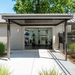 Modern outdoor gym facility with state-of-the-art equipment and vibrant exercise setup, surrounded by lush greenery.
