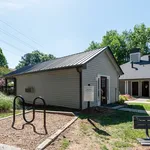Charming outdoor view of a modern community building with sleek siding, surrounded by lush greenery and open blue skies.