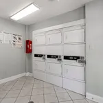 Bright and efficient laundry room with modern, stacked washers and dryers, tiled flooring, and clear usage instructions for convenience.