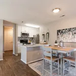Modern kitchen and dining area with sleek white cabinetry, stainless steel appliances, and a cozy wooden dining set, perfect for entertaining.