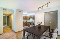 Inviting apartment interior with a cozy dining area adjacent to a modern kitchen featuring sleek wooden cabinets and stylish lighting.