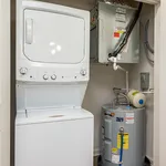 Modern laundry room with a sleek stacked washer and dryer set, complemented by energy-efficient water heater.