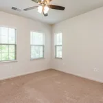 Bright and airy room with plush carpeting and large windows, enhanced by a modern ceiling fan.