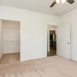 Modern bedroom with walk-in closet and view into a sleek kitchen with stainless steel appliances, offering a blend of comfort and style.