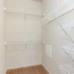Spacious walk-in closet with sleek white shelving, perfect for organized storage and maximizing space.