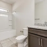 Modern bathroom with elegant granite countertop, sleek cabinetry, and a spacious bathtub with glass enclosure.