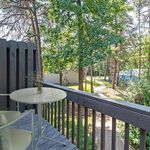 Charming balcony with a cozy table set overlooking lush greenery and a peaceful path.