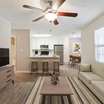Charming open-concept living room with a cozy couch, modern kitchen with stainless steel appliances, and elegant dining area. Perfect for stylish urban living.