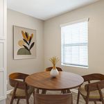 Charming dining nook with a round wooden table, elegant chairs, and contemporary artwork, bathed in natural light.