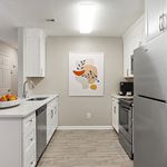 Modern kitchen with sleek white cabinetry, stainless steel appliances, and elegant wall art, offering a bright and inviting cooking space.