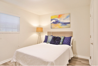 Bright and inviting bedroom with modern artwork, stylish bed set, and warm lighting fixture.