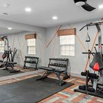 Modern fitness room featuring a sleek bench, versatile weight machine, and reflective mirrors enhancing a dynamic workout space.