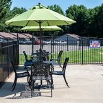 Charming outdoor patio with elegant wrought iron furniture and a vibrant green umbrella, offering a perfect space for relaxation and outdoor dining.