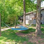Charming outdoor area featuring a relaxing hammock between trees, perfect for enjoying nature in a serene apartment setting.