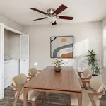 Elegant dining room with a wooden table, stylish chairs, and modern art on the wall, featuring natural light and a ceiling fan.