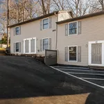 Charming duplex exterior showcasing modern siding, individual entrances, and convenient parking spaces in a serene natural setting.