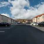Charming apartment complex with ample parking under a beautifully clear sky, offering a serene and welcoming neighborhood atmosphere.