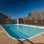 Inviting outdoor swimming pool with crystal clear water, surrounded by a serene natural landscape and sun loungers, perfect for relaxation.