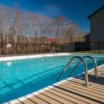 Inviting outdoor swimming pool with lounge chairs and fenced railing, surrounded by scenic trees on a sunny day.