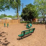 Inviting outdoor dog park with agility equipment and benches, set against a backdrop of lush green trees and sunny skies.