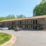 Charming two-story apartment complex with spacious parking and lush green surroundings.