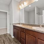 Modern bathroom with elegant dual sinks, granite countertop, and sleek cabinetry, offering a touch of luxury.