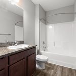 Elegant bathroom with modern fixtures, sleek granite countertop, and a pristine bathtub, set against stylish gray walls.