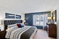 Inviting bedroom with a plush tufted headboard, stylish bedding, and a sunlit window offering serene views.