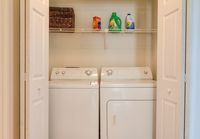 Convenient in-unit laundry space featuring a modern washer and dryer with ample shelf storage.