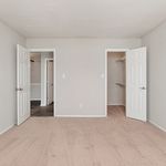 Bright bedroom with plush carpeting, featuring dual doors leading to a spacious walk-in closet and adjacent room, highlighting ample storage and versatile layout.