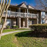 Charming two-story apartment building with private balconies, surrounded by lush greenery and well-maintained landscaping.