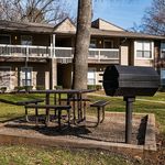 Charming apartment community with a welcoming picnic area and barbecue grill, surrounded by lush greenery.