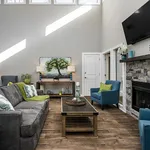 Bright, inviting living room with vaulted ceilings, elegant stone fireplace, and stylish modern furnishings.