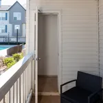 Charming patio with white siding and cozy seating, overlooking a lush garden and sparkling swimming pool.